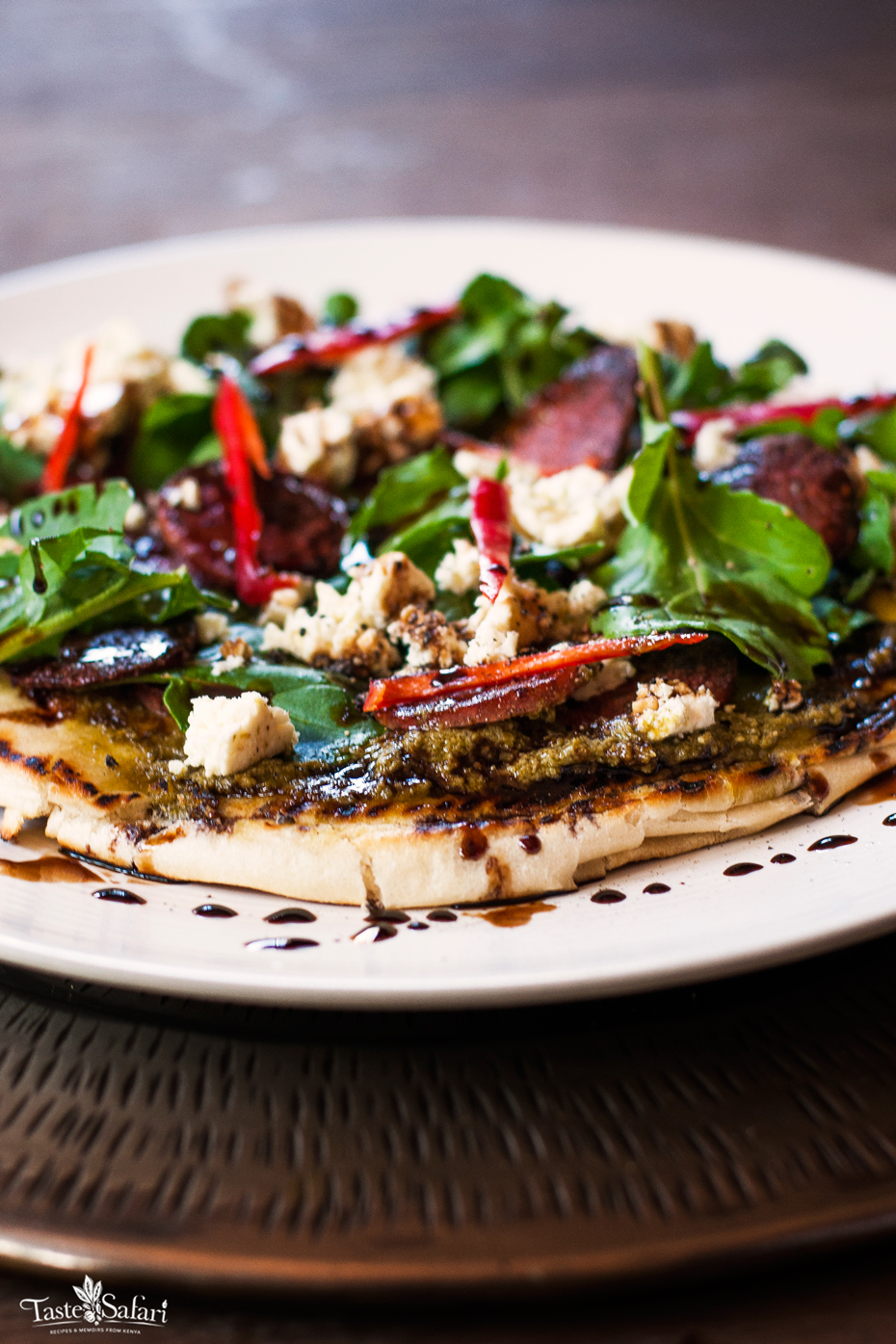 Finished salami pizza topped with rucola, feta and balsamic drizzle